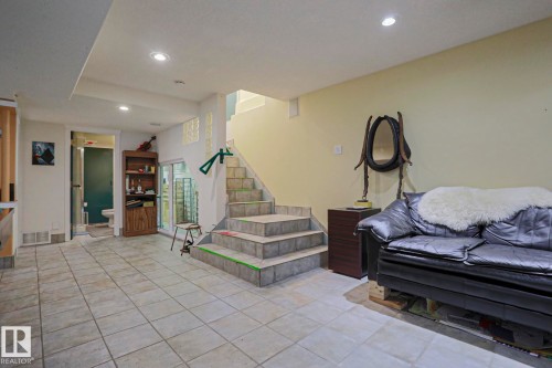Recessed lighting illuminates the tiled flooring and staircase with stone-finish treads - 10814 125 Street Nw, Edmonton, AB 