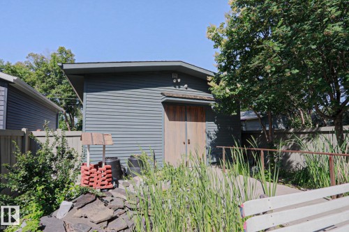 Exterior outbuilding featuring horizontal siding, a shed roofline, and natural wood doors - 10814 125 Street Nw, Edmonton, AB 