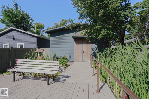 Composite decking with a ramp leading to a structure featuring wood-paneled doors and horizontal siding - 10814 125 Street Nw, Edmonton, AB 