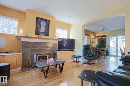 Hardwood flooring, fireplace with stone surround, arched doorway, glass block windows, built-in cabinetry - 10814 125 Street Nw, Edmonton, AB 