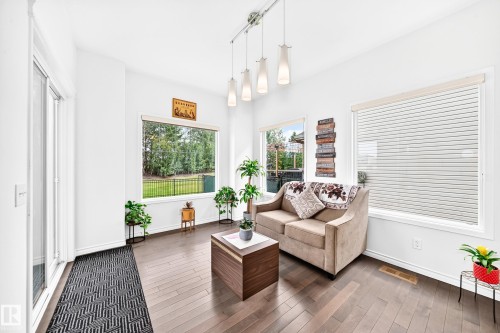 Hardwood-finish flooring, white walls, multiple large windows, sliding glass door, and track lighting with pendant fixtures - 2015 Chalmers Way Sw, Edmonton, AB 