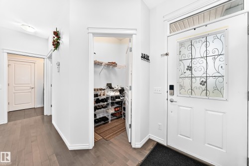 Entryway with light wood-finish flooring, white paneled doors, and a decorative frosted glass front door - 2015 Chalmers Way Sw, Edmonton, AB 
