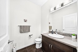 Wood-finish vanity with a surface-mount sink, dark countertop, and mosaic tile backsplash - 