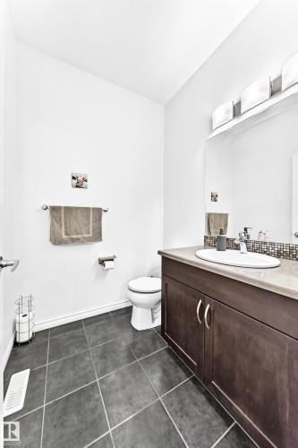 Dark-toned floor tiling, white walls, and a vanity with a light-toned countertop and integrated sink - 2015 Chalmers Way Sw, Edmonton, AB 