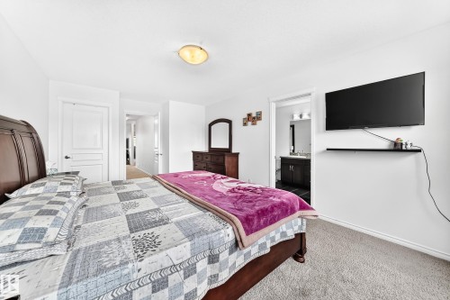 White painted walls, neutral carpet flooring, recessed ceiling light fixture, dark wood-finish dresser with mirror, and a dark wood-finish bed frame - 2015 Chalmers Way Sw, Edmonton, AB 