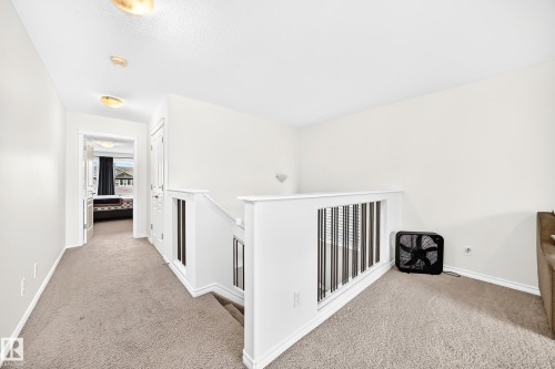 Carpeted landing with white walls and a white spindle railing - 2015 Chalmers Way Sw, Edmonton, AB 