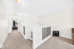 Carpeted landing with white walls and a white spindle railing - 