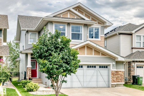 Two-story facade with light gray siding, stone accents, and a red entry door - 2015 Chalmers Way Sw, Edmonton, AB 