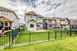 Two-story home with light-colored siding, a rear patio, and an expansive lawn - 