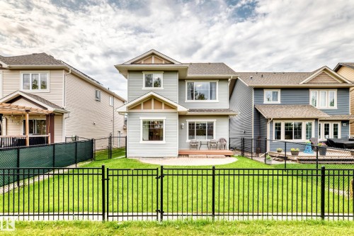 Fenced backyard featuring a manicured lawn, a ground-level deck, and a paved patio area - 2015 Chalmers Way Sw, Edmonton, AB 
