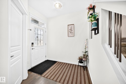 Entryway featuring wood-finish flooring, white paneled door with decorative glass, and a flush-mount ceiling light - 2015 Chalmers Way Sw, Edmonton, AB 