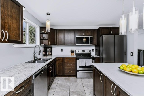 Kitchen featuring dark wood cabinetry, light-toned countertops, stainless steel appliances, and tile flooring - 18431 95A Avenue Nw, Edmonton, AB 