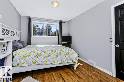 Wood-finish flooring, neutral wall tones, window with exterior scenery, white trim, and a black paneled door - 18431 95A Avenue Nw, Edmonton, AB 