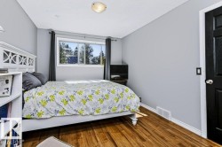 Wood-finish flooring, neutral wall tones, window with exterior scenery, white trim, and a black paneled door - 