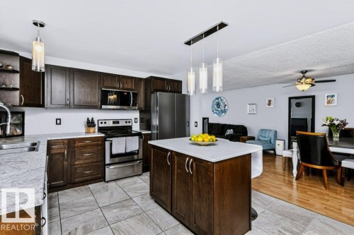 Kitchen featuring dark wood cabinetry, light-toned countertops, stainless steel appliances, and tile flooring - 18431 95A Avenue Nw, Edmonton, AB 