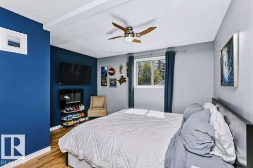 Wood-finish flooring with a ceiling fan, exposed ceiling beams, and a window with curtains - 18431 95A Avenue Nw, Edmonton, AB 