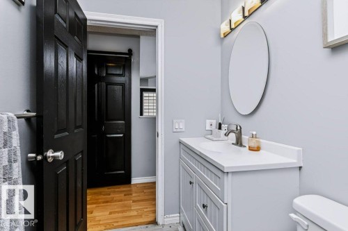 Bathroom featuring a vanity with an integrated sink, brushed nickel faucet, oval mirror, and a contemporary light fixture - 18431 95A Avenue Nw, Edmonton, AB 