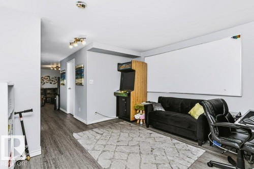 Spacious recreation room featuring wood-finish flooring, a large whiteboard wall, recessed lighting throughout, and built-in cabinetry - 18431 95A Avenue Nw, Edmonton, AB 