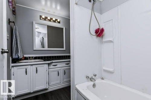 White vanity with dark hardware, a single basin sink, and a framed mirror - 18431 95A Avenue Nw, Edmonton, AB 