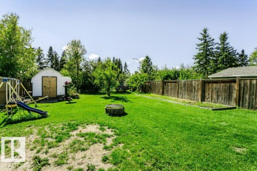 Expansive grassy yard featuring mature trees, a storage shed with double doors, and wood fencing - 18431 95A Avenue Nw, Edmonton, AB 