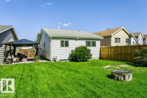 Expansive backyard featuring a concrete patio, a detached gazebo, a wood privacy fence, and a built-in fire pit area - 18431 95A Avenue Nw, Edmonton, AB 
