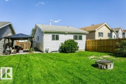 Expansive backyard featuring a concrete patio, a detached gazebo, a wood privacy fence, and a built-in fire pit area - 