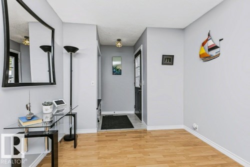 Light wood-finish flooring with white trim, light gray wall paint, and a front entry door with glass paneling - 18431 95A Avenue Nw, Edmonton, AB 