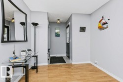 Light wood-finish flooring with white trim, light gray wall paint, and a front entry door with glass paneling - 
