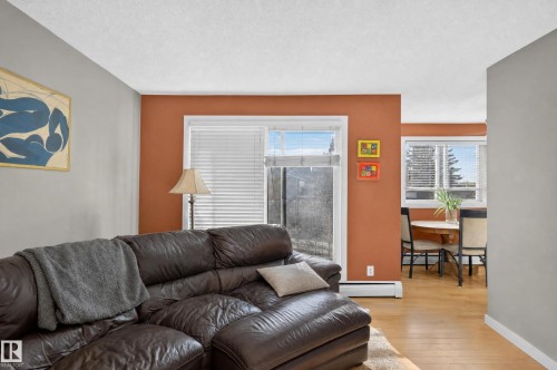 Wood-finish flooring throughout, complemented by a sliding glass door and an additional window - #204 7407 171 St Nw, Edmonton, AB 