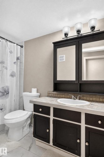 Vanity featuring dark wood-finish cabinetry, integrated sink, and an overhead lighting fixture - #204 7407 171 St Nw, Edmonton, AB 