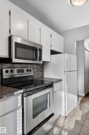 White cabinetry, stainless steel appliances, mosaic tile backsplash, and stone-finish countertops - 