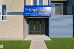 Building entrance with a blue awning, glass doors, and a concrete pathway - 