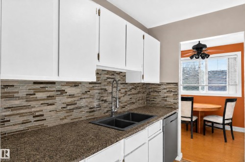 White cabinetry, mosaic tile backsplash, double basin sink, stone-finish countertops, and stainless steel dishwasher - #204 7407 171 St Nw, Edmonton, AB 