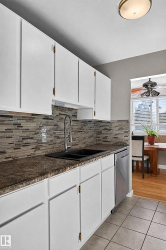 White cabinetry with brass hardware, speckled countertops, and a full tile backsplash - #204 7407 171 St Nw, Edmonton, AB 