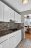 White cabinetry with brass hardware, speckled countertops, and a full tile backsplash - #204 7407 171 St Nw, Edmonton, AB 