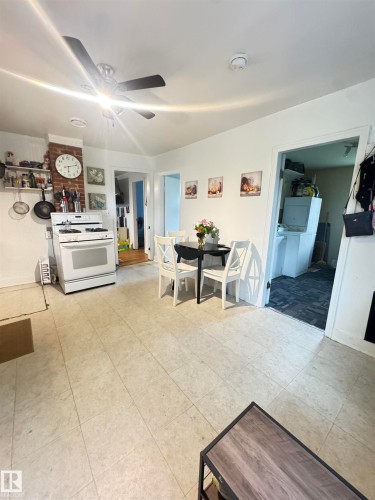 Kitchen area featuring a white gas range, tiled flooring, exposed brick accent, and a ceiling fan with integrated lighting - 5019 48 Avenue, Onoway, AB - Indoor