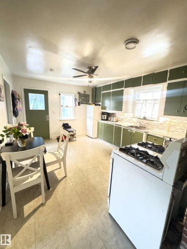 Kitchen featuring green cabinetry, tile flooring, and white appliances - 5019 48 Avenue, Onoway, AB - Indoor