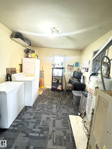 Utility space with patterned carpet flooring, a single window, track lighting, and a wall-mounted shelf - 5019 48 Avenue, Onoway, AB - Indoor Photo Showing Laundry Room