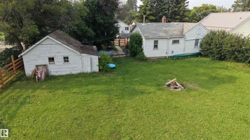 Expansive green space featuring a white wood-sided shed with a shingle roof and two windows, and a home to match - 5019 48 Avenue, Onoway, AB - Outdoor
