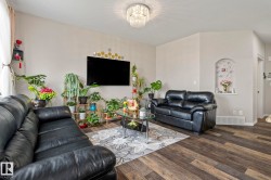 Living area featuring wood-finish flooring, a crystal chandelier, and an arched wall niche - 