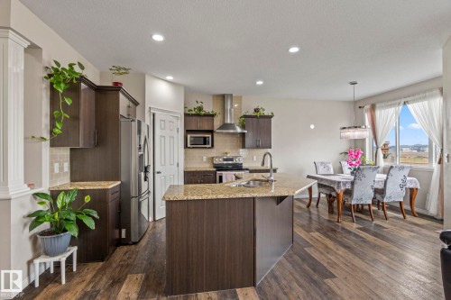 Open-concept kitchen featuring wood-finish flooring, dark wood cabinetry, and granite countertops - 2131 51 Sw, Edmonton, AB - Indoor Photo Showing Kitchen With Upgraded Kitchen