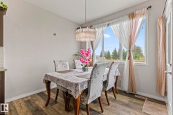 Spacious dining area featuring wood-finish flooring, a large window, and a contemporary chandelier - 