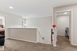 Upper-level landing with plush carpeting and a contemporary tiered pendant light fixture - 