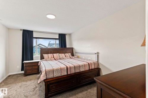 Carpeted bedroom with a large window, dark curtains, and a ceiling-mounted light fixture - 2131 51 Sw, Edmonton, AB - Indoor Photo Showing Bedroom