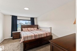 Carpeted bedroom with a large window, dark curtains, and a ceiling-mounted light fixture - 