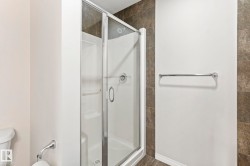 Glass-enclosed shower stall with a white base and silver-toned hardware - 