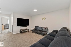 Spacious carpeted room featuring a wall-mounted flat-screen television - 