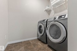 Dedicated laundry area featuring tile flooring, white baseboards, and wire shelving - 