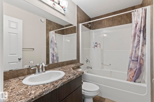 Bathroom featuring a vanity with an undermount sink, a chrome faucet, and a stone-finish countertop - 2131 51 Sw, Edmonton, AB - Indoor Photo Showing Bathroom