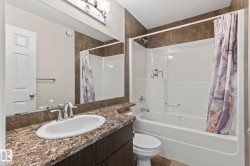 Bathroom featuring a vanity with an undermount sink, a chrome faucet, and a stone-finish countertop - 